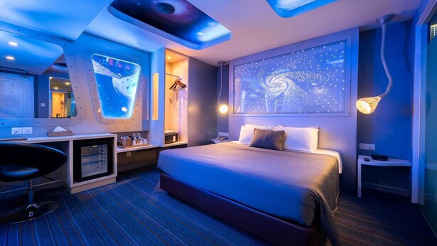 A modern hotel room with a large bed, a desk, and a wall with a galaxy-themed light display. - Kingston Hotel 3 @ Kuala Lumpur (Kuala Lumpur)
