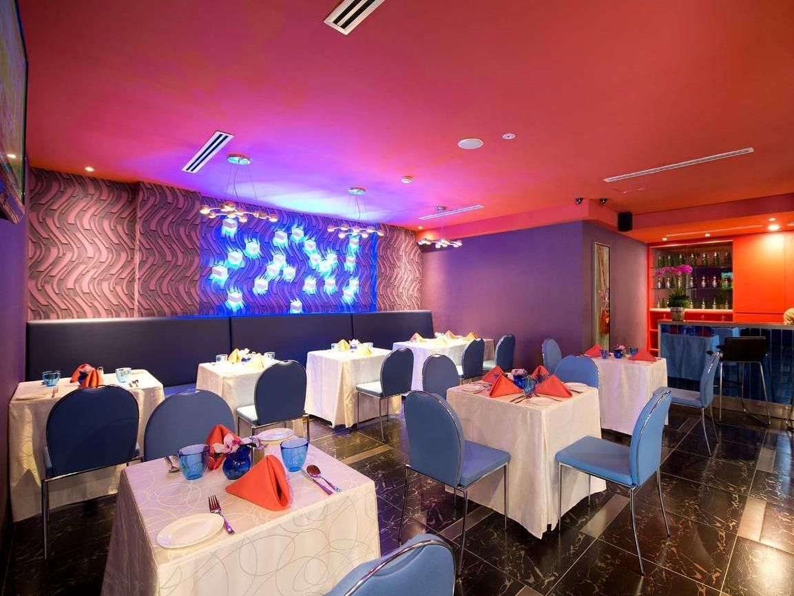 A dining area with tables set for multiple guests, a bar area with bottles, and a decorative wall with lights.