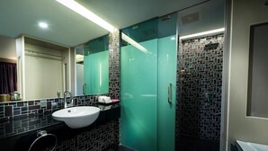 Een moderne badkamer met een wit wastafelmeubel, een douchecabine met glazen wanden en een betegelde spatwand.