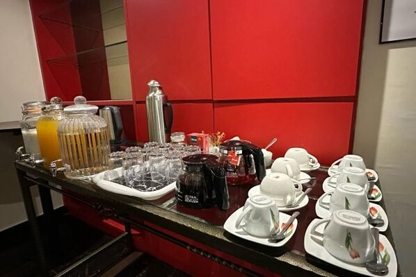Ein Frühstücksbuffet mit verschiedenen Speisen und Getränken, darunter eine Kaffeestation und eine Auswahl an Früchten.