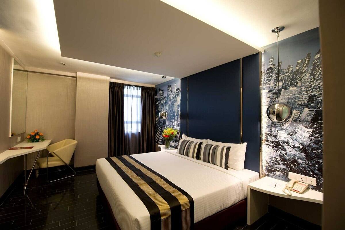 Una habitación de hotel moderna con cama, mesita de noche, silla y un mural de paisaje urbano en la pared.