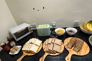 Eine Küchenarbeitsplatte mit einem Toaster, einem Mixer und verschiedenen Lebensmitteln, darunter Brotscheiben und Schüsseln mit Müsli.