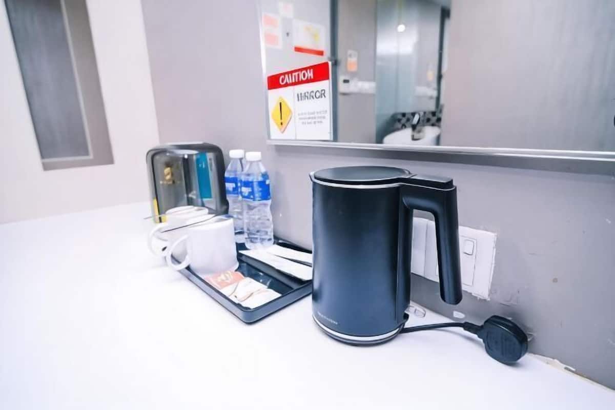 Mostrador de hotel con cafetera, botellas de agua y un letrero de precaución.