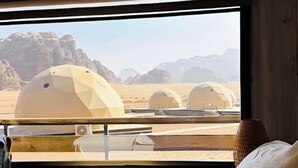 Une chambre avec un lit, une fenêtre et une vue sur les tentes du désert.