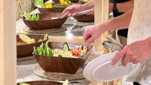 Un buffet proposant divers plats, avec une personne chargée de servir les aliments.