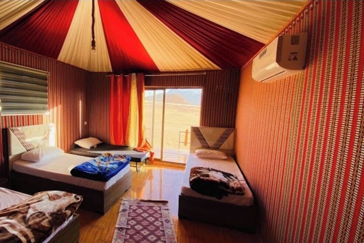 A tent-style room with a bed, a sofa, a small table, and a window with curtains.