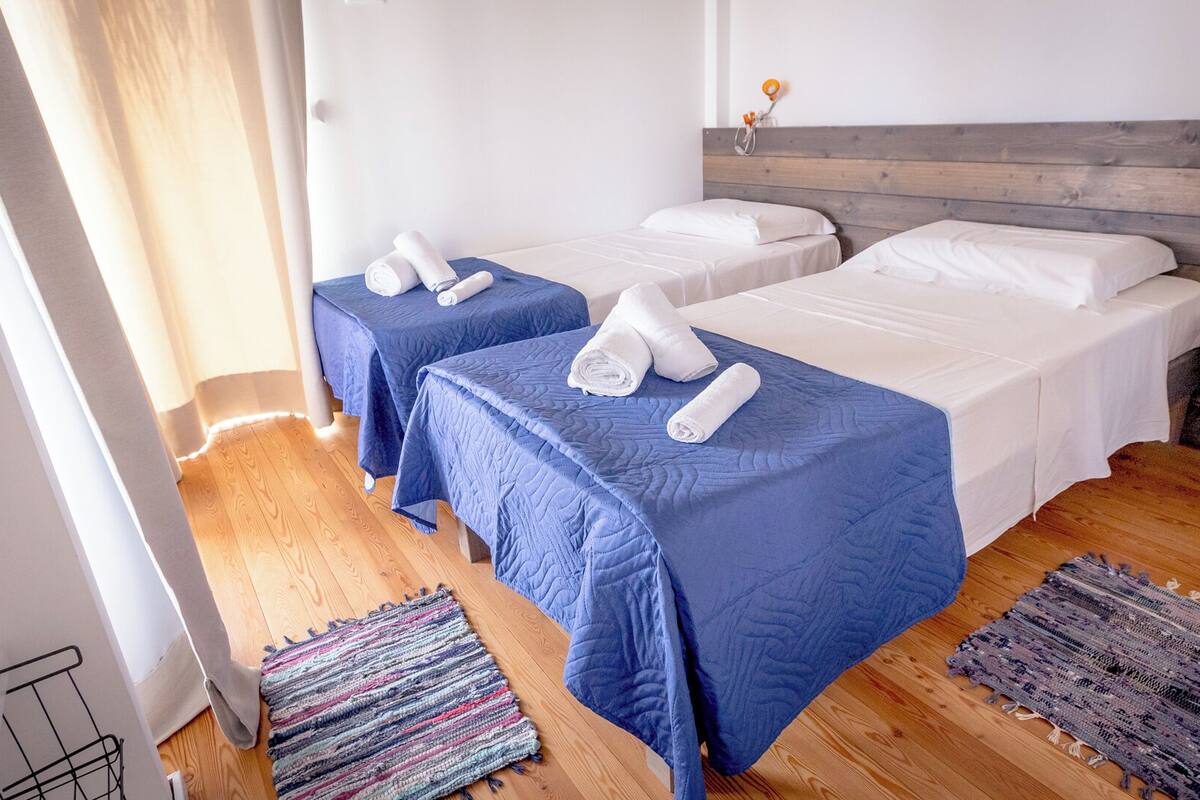 A hotel room with two single beds, a wooden headboard, and a small rug on the floor.