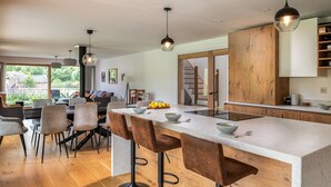 Une cuisine moderne dotée d’un îlot central, de meubles en bois et de luminaires suspendus.