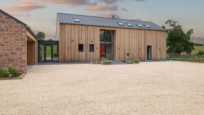 Un bâtiment moderne avec une allée en gravier, un revêtement extérieur en bois et une porte rouge.