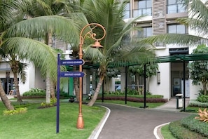 Un sendero conduce a un edificio con un cartel que indica las direcciones a la recepción y la entrada de servicio.
