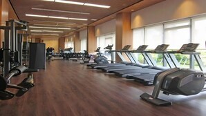A gym with treadmills, weight machines, and a wooden floor. - Calma 2BR II @Skyhouse Apartment (Cisauk)