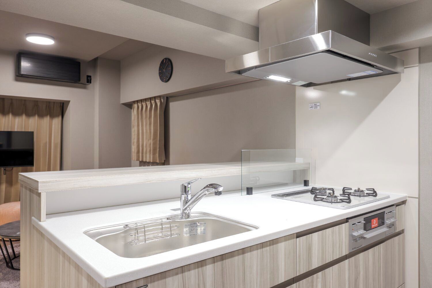 Una cocina moderna con un extractor de acero inoxidable, un lavamanos doble y un horno empotrado.