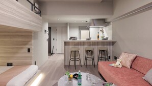 Ein modernes Wohnzimmer mit einer Couch, einem Couchtisch mit Getränken und einer Küche im Hintergrund.