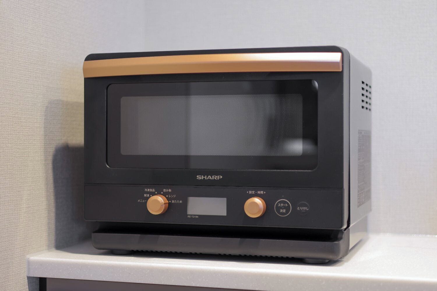 A black Sharp microwave oven with a control panel, placed on a white surface.