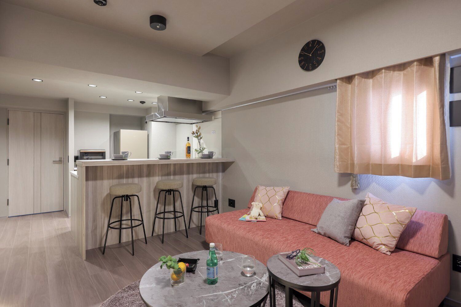 A modern living room with a sofa, a coffee table, and a kitchen area with a bar stool.
