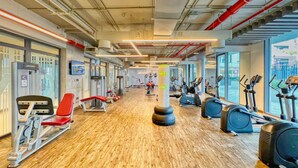 A gym with cardio equipment, weight machines, and a wooden floor. - Cove Residences - Creek Harbour Dubai (Dubai)