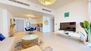 A modern living room with a TV, sofa, and dining area. - Cove Residences - Creek Harbour Dubai (Dubai)