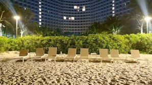 A beach with lounge chairs and a hotel building in the background. - Sun SeaView Cam Ranh Resort (Cam Ranh)