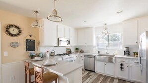 A modern kitchen with white cabinetry, stainless steel appliances, and a central island with bar stools. - Vineyard & Valley View Cottage w/hot tub
Tranquil Farmhouse w/stunning sunsets. (Templeton)
