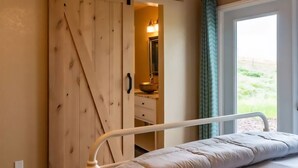 A bedroom with a bed, a wooden wardrobe, a bathroom with a mirror, and a window with a view. - Vineyard & Valley View Cottage w/hot tub
Tranquil Farmhouse w/stunning sunsets. (Templeton)