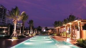 A swimming pool with palm trees and a covered area, surrounded by buildings. - Mirror Mirror Hotel Cafe & Restaurant (Klaeng)