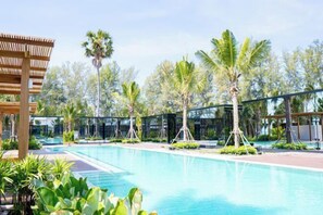 A swimming pool with surrounding palm trees and a covered seating area. - Mirror Mirror Hotel Cafe & Restaurant (Klaeng)
