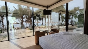 A bedroom with a large bed, a TV, and a view of the beach. - Mirror Mirror Hotel Cafe & Restaurant (Klaeng)