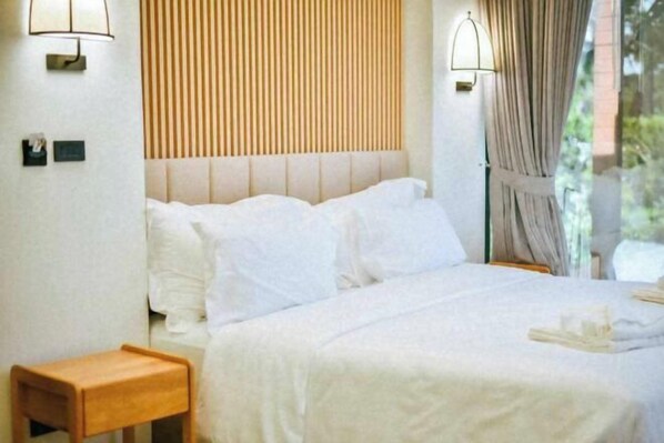 A bed with white linens, a wooden headboard, and a nightstand with a lamp. - Mirror Mirror Hotel Cafe & Restaurant (Klaeng)