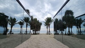 A beach with a sandy path leading to the sea, flanked by palm trees and a clear sky. - Mirror Mirror Hotel Cafe & Restaurant (Klaeng)