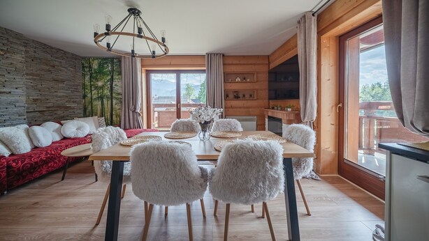 Un'accogliente zona pranzo con un tavolo in legno, poltrone soffici e un lampadario.