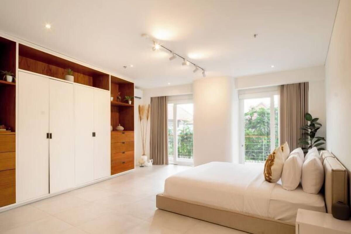 Un dormitorio moderno con una cama grande, armario empotrado y vistas a zonas verdes.