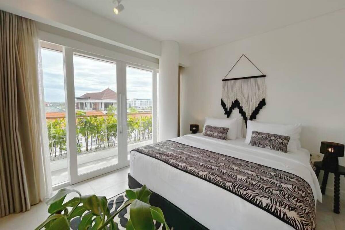 Un dormitorio con una cama grande, vistas al exterior y un adorno en la pared.