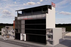 A modern building with a large garage entrance, a signboard, and a white car on the street. - AN HOTEL (Bac Ninh)