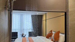Ein Hotelzimmer mit Bett, Dusche und Blick auf einen Balkon mit Vorhängen.