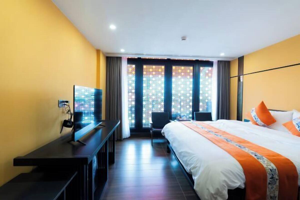 A hotel room with a bed, a desk, a chair, and a TV.
