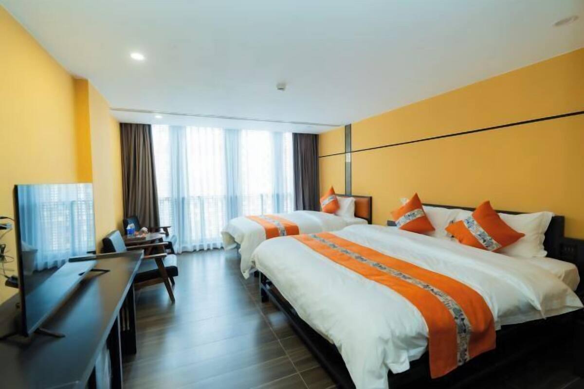 A hotel room with two beds, a desk, and a TV.
