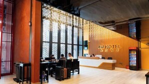 Ein Hotel-Rezeptionsbereich mit modernem Design, ausgestattet mit einer Rezeption, einer Sitzgelegenheit und großen Fenstern für natürliches Licht.