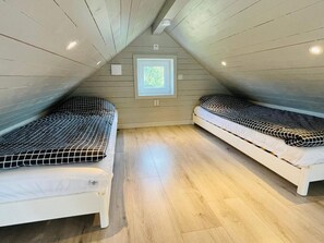 A small attic bedroom with two beds, wooden flooring, and a window. - 4 Star Holiday Home in Solvesborg (Sölvesborg)