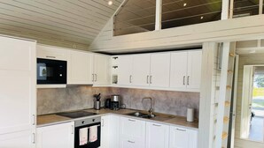 A modern kitchen with white cabinetry, a built-in microwave, a coffee maker, and a sink. - 4 Star Holiday Home in Solvesborg (Sölvesborg)