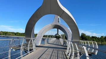 Uma ponte para pedestres com deck de madeira e grades de metal.