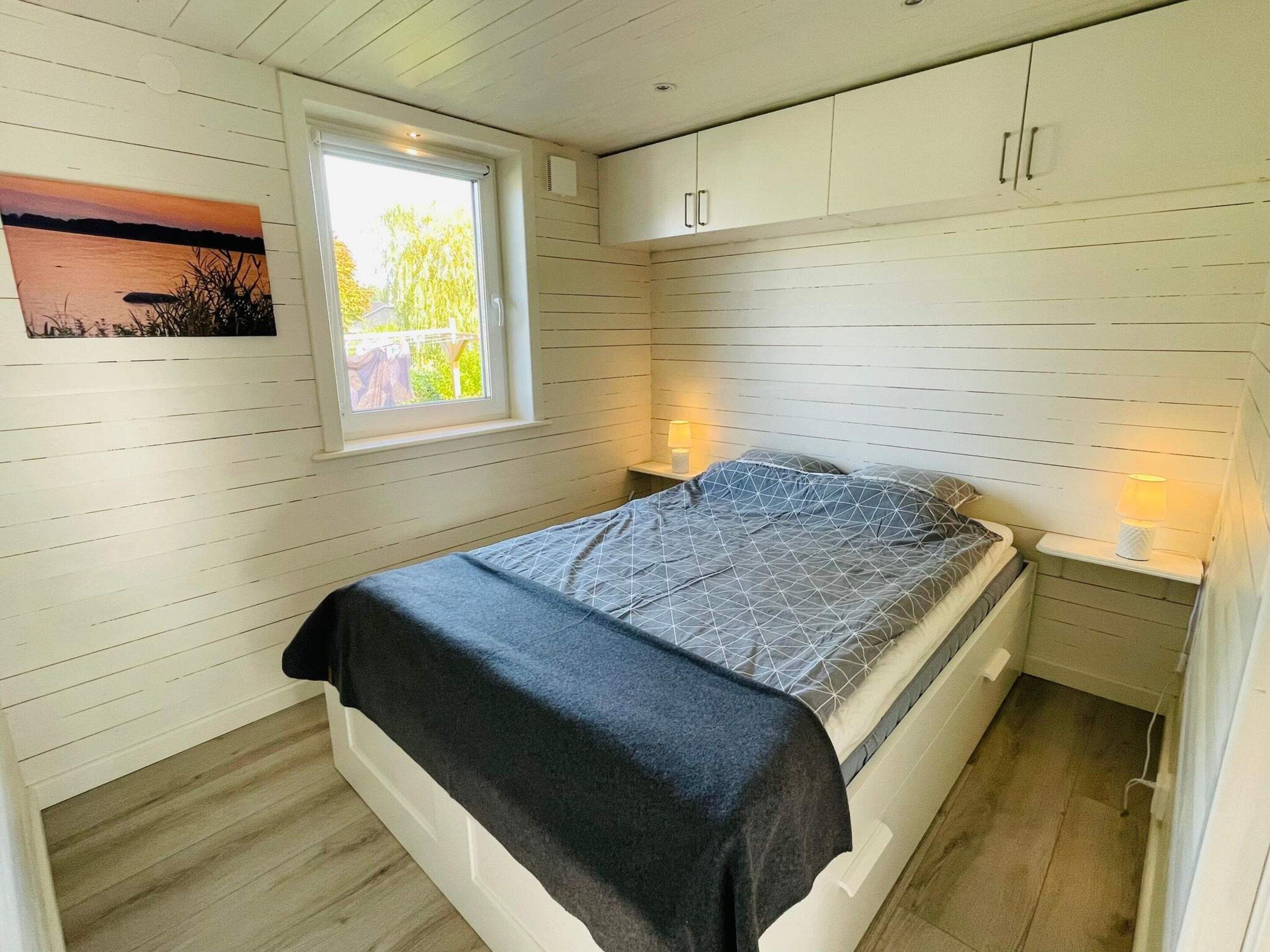 A bedroom with a bed, a window, and a wall-mounted cabinet.