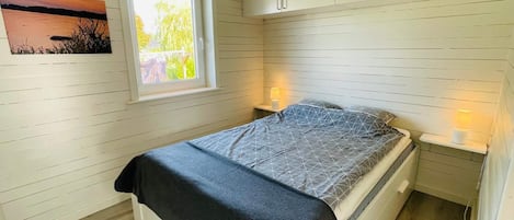 A bedroom with a bed, a window, and a wall-mounted cabinet.