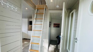 A narrow hallway with a white ladder leading to a lofted area. A door on the right leads to another room. - 4 Star Holiday Home in Solvesborg (Sölvesborg)