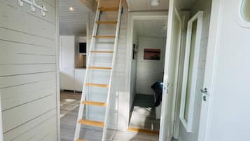 Un pasillo estrecho con una escalera de madera blanca que conduce a una zona elevada.