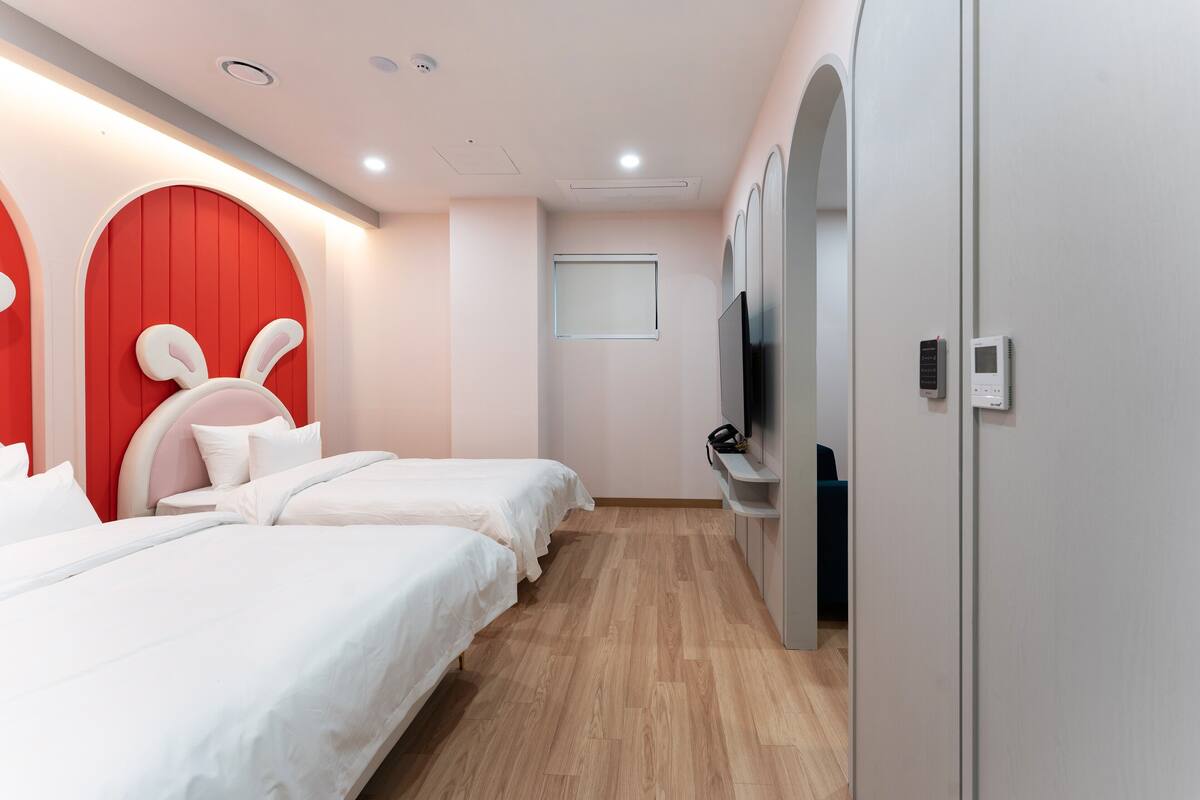 A hotel room with two beds, a TV, a wardrobe, and a window.