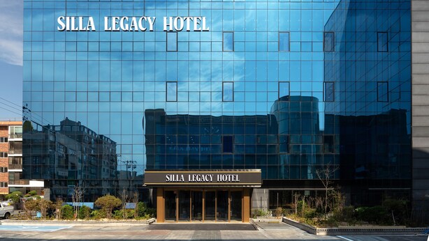 Un hotel moderno con fachada de vidrio reflectante y el nombre "Silla Legacy Hotel" visible en grande.