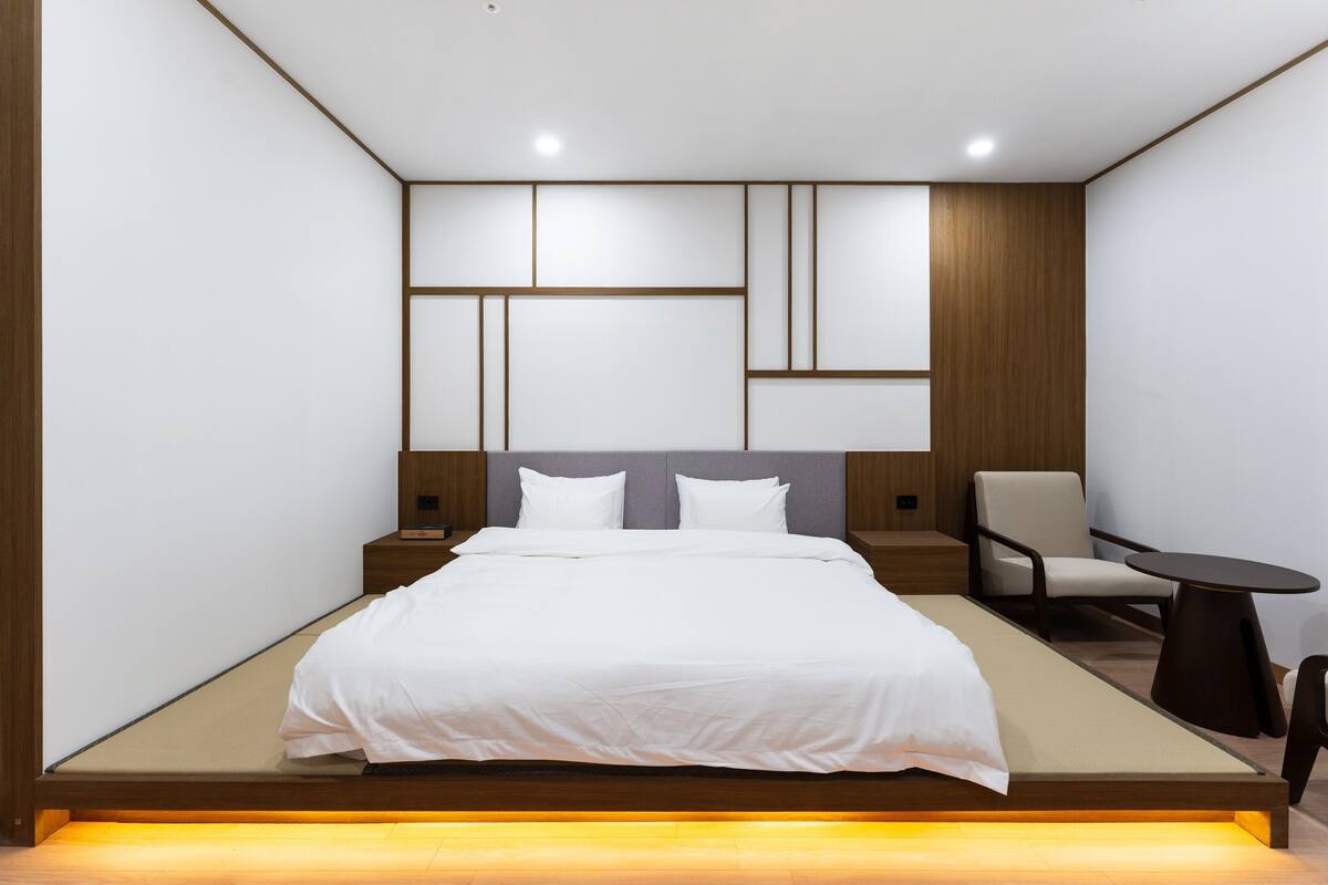 A modern bedroom with a bed, bedside tables, a chair, and a small table.