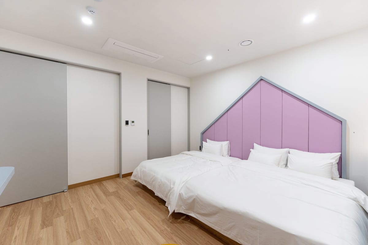 A bedroom with a bed, a door, and a wall with a unique headboard design.