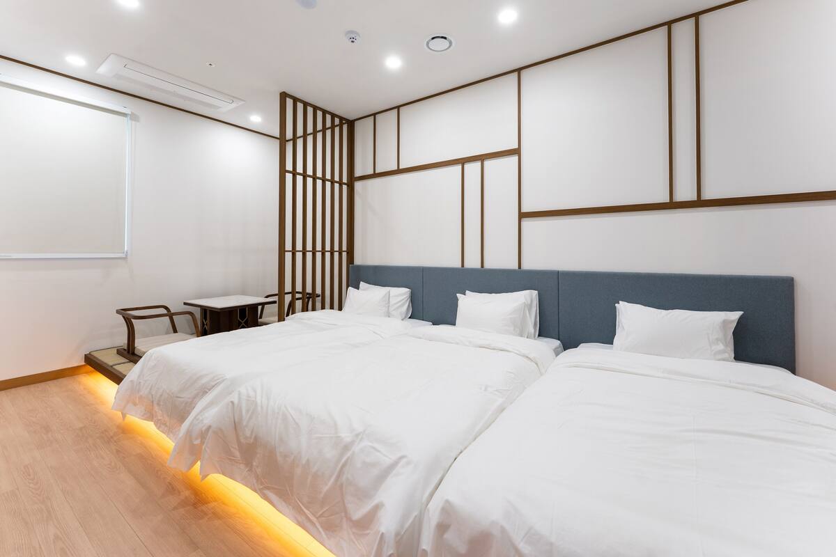 A modern hotel room with a large bed, a desk, and a view of the city.