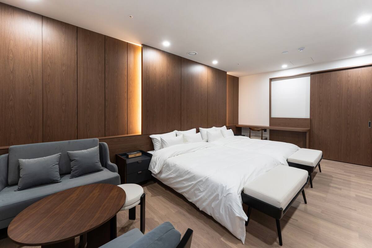 A modern bedroom with a large bed, a sofa, a small table, and a desk.